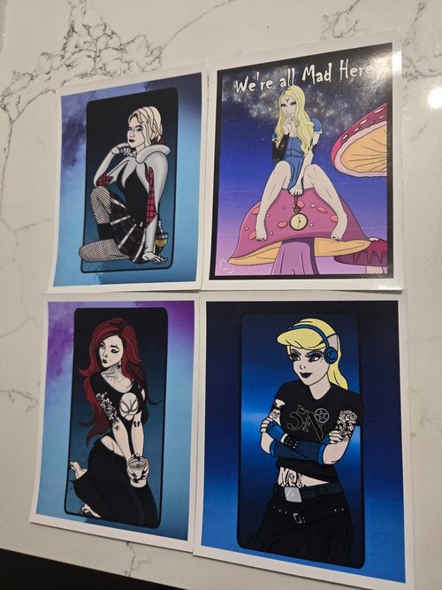 Rock Princess Postcards, a pack of 4 goth-reimagined princess prints: a Spider-Gwen-style heroine, a "We're all Mad Here" Alice on a giant mushroom, a tattooed redhead with coffee, and a headphone-wearing metalhead blonde.