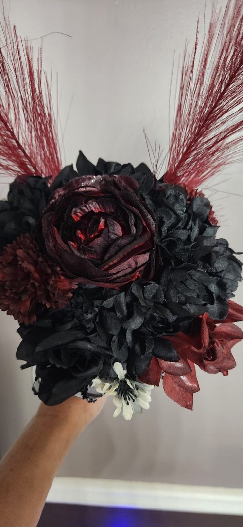 Our Red bouquet is a gothic showstopper, with a glittery burgundy rose at its heart, surrounded by black blooms, deep red accents, and tall crimson plumes. Spooky, dramatic, and made to be noticed.